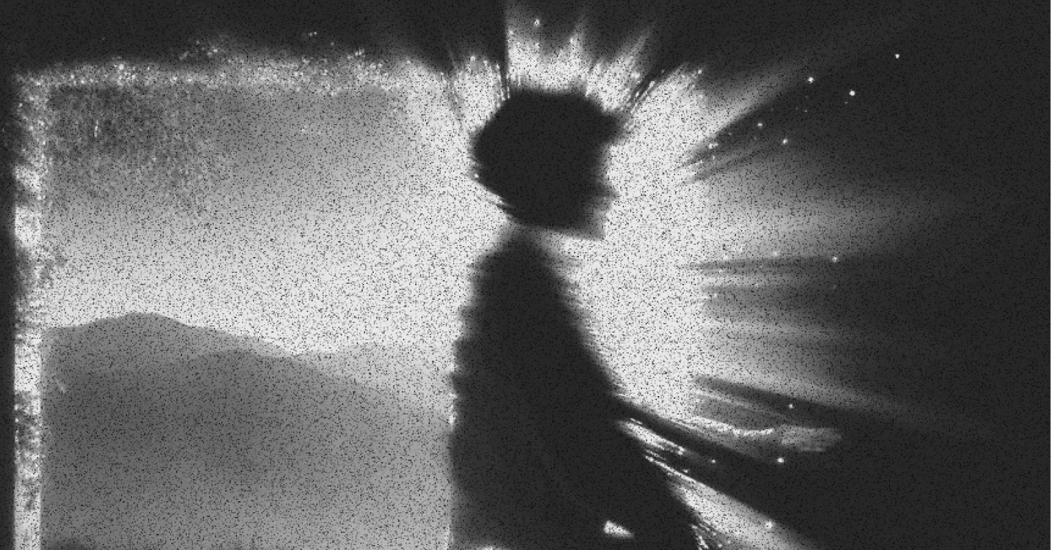 A shadowed figure moving past a bright screen with blurred hands reaching in.